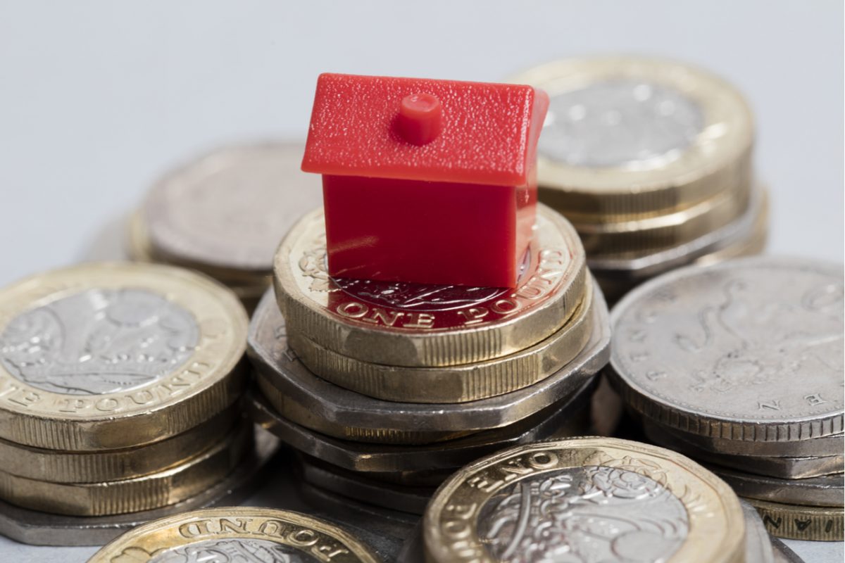 Plastic red house sitting on top of a pile of money