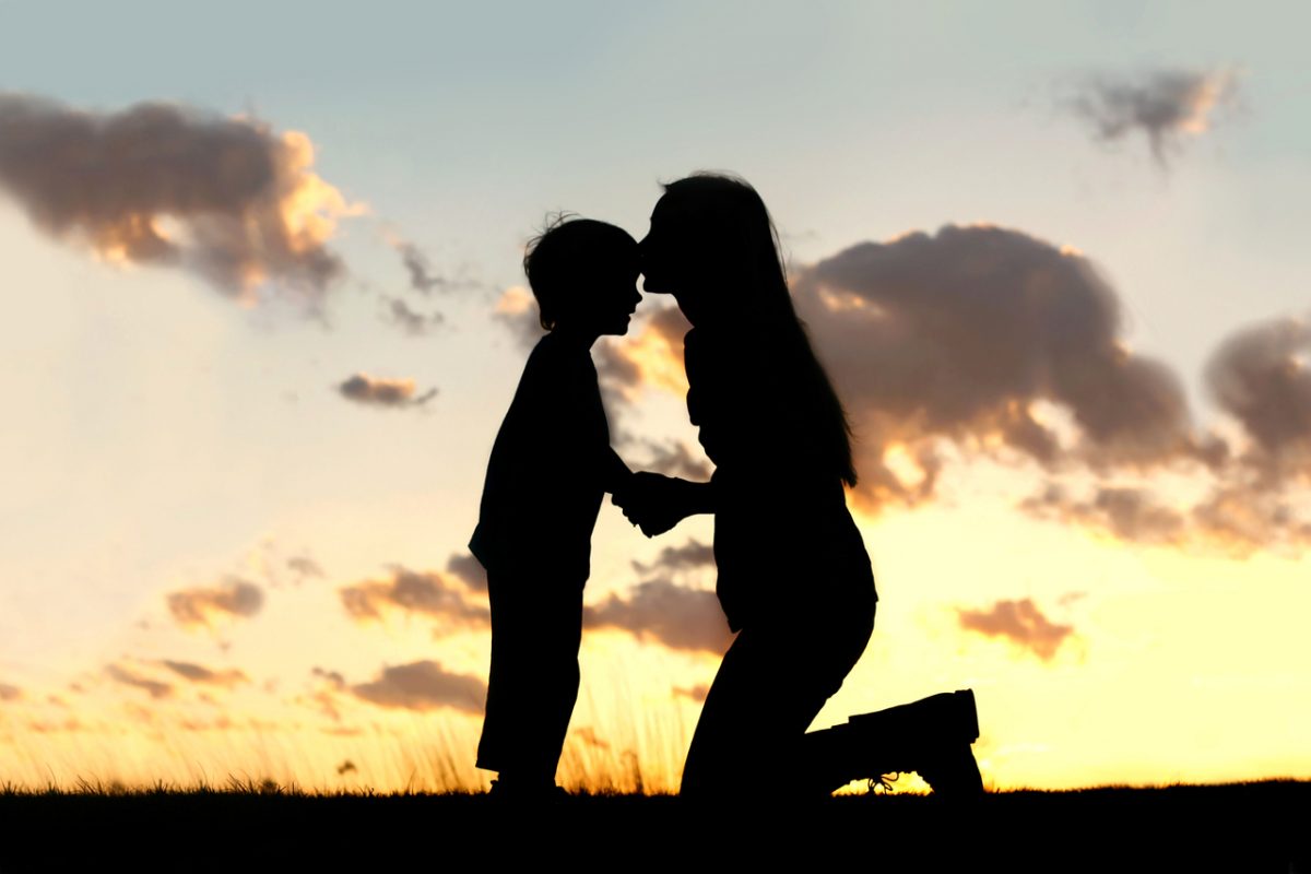 Silhouette of mother kissing her son on the head