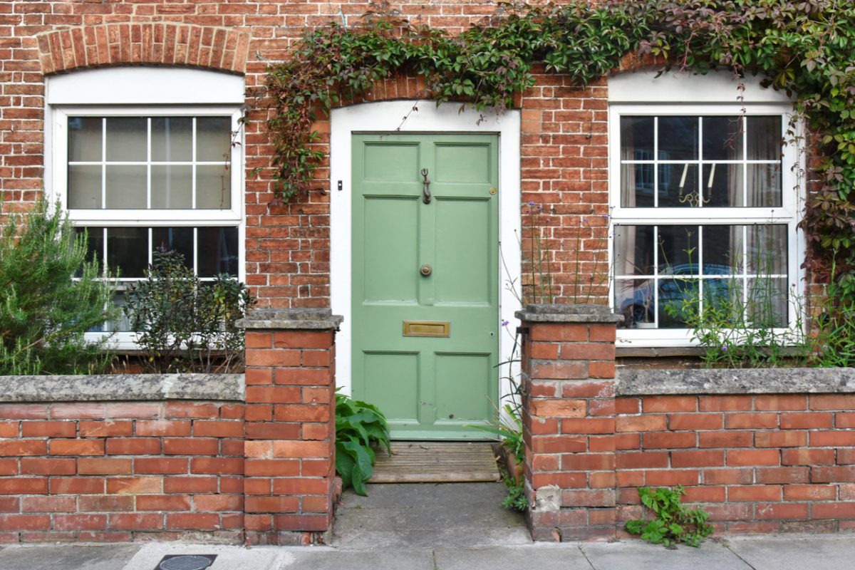 Green front door to home surrounded by plants