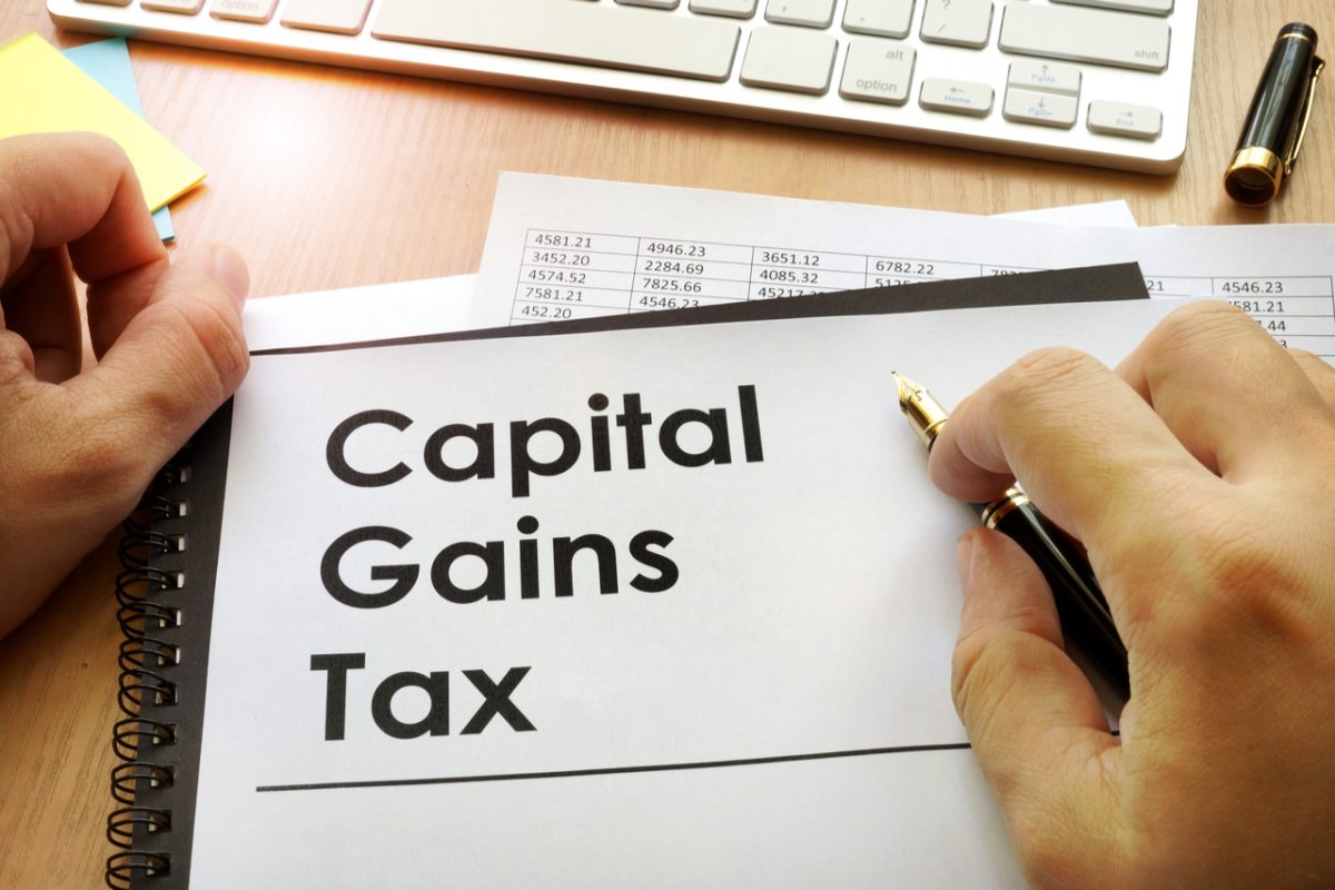 Hands holding a document that says “Capital Gains Tax”