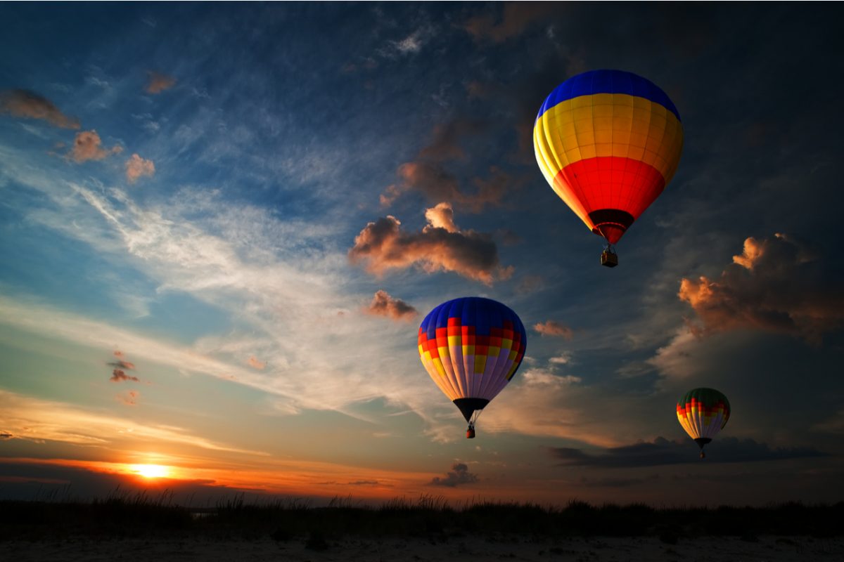 Three colourful hot air balloons flying at sunrise