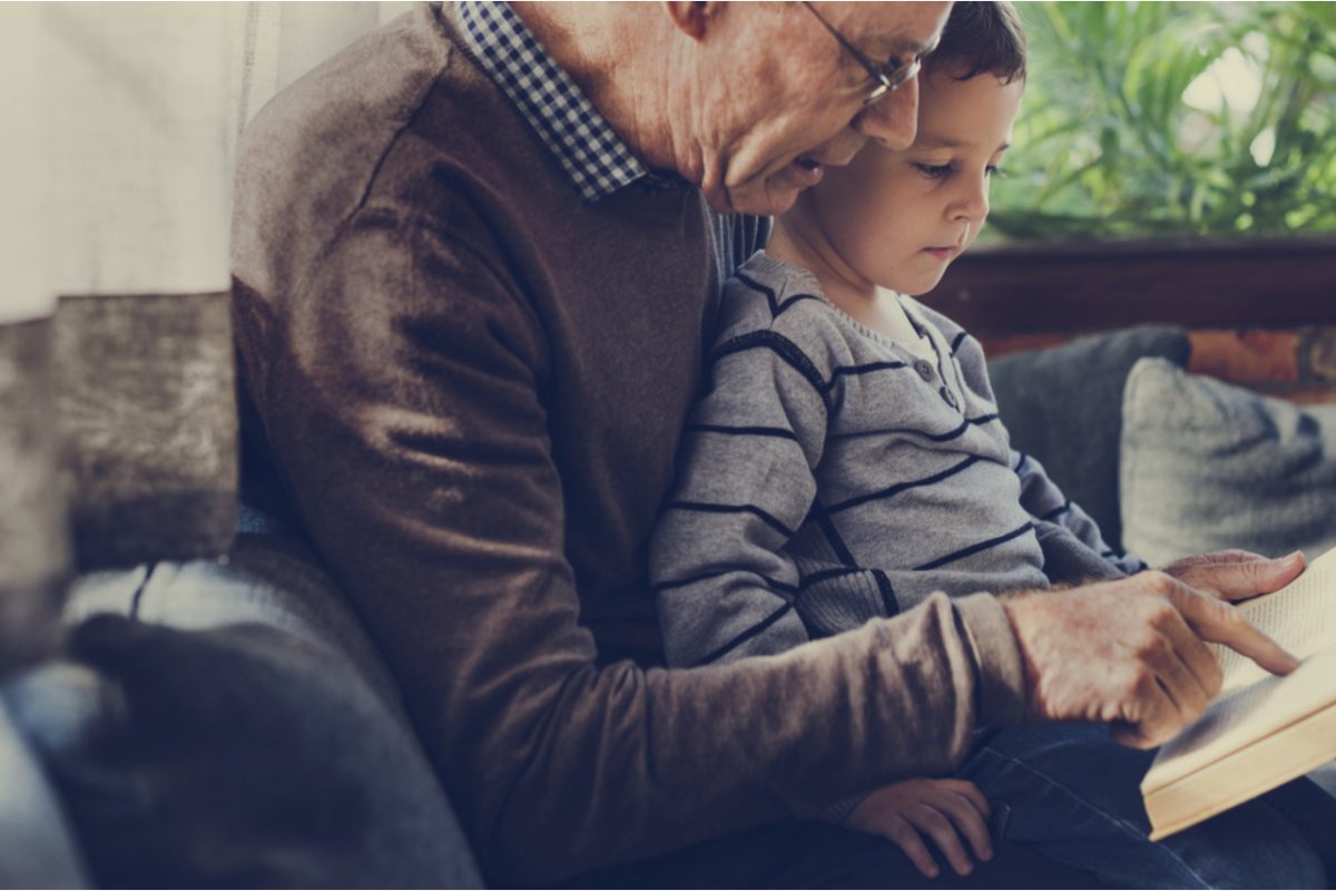 A grandfather and grandson reading a book together