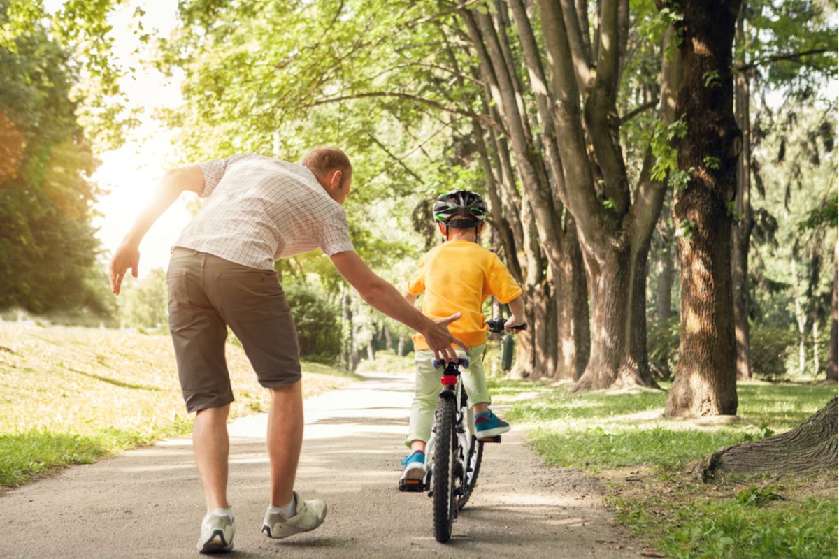 A father teaching his young son to ride a bike.