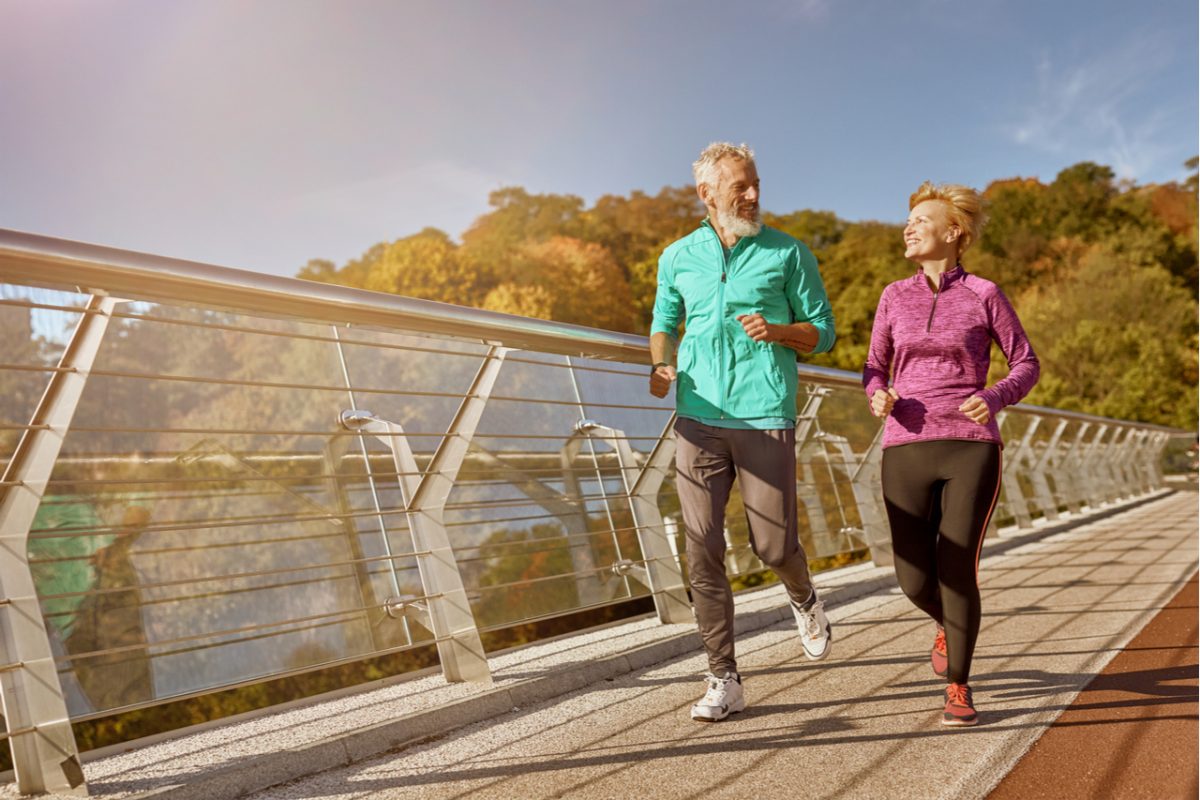 A mature couple jogging across a bridge.