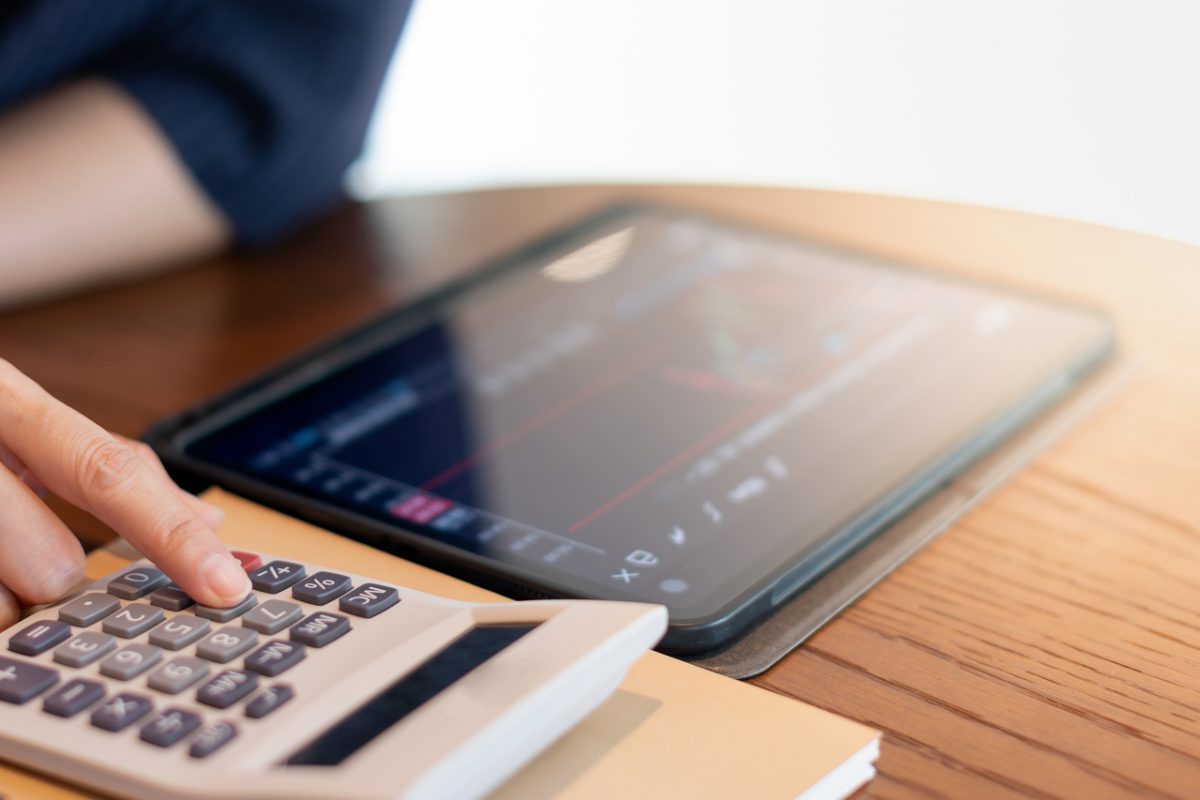 A person using a calculator while looking at a graph on a tablet.