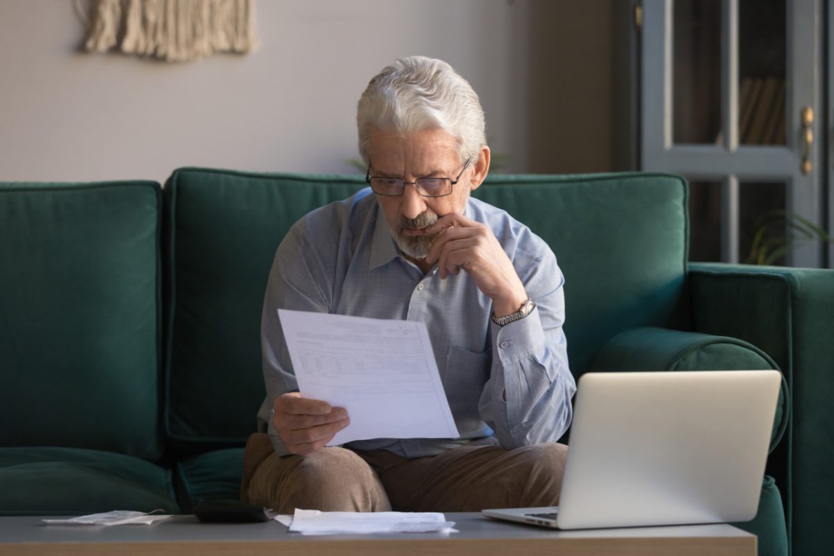 An older man reviewing some paperwork at home.