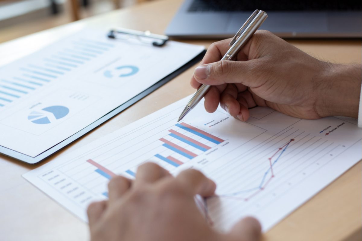 A person reviewing graph data on paper.