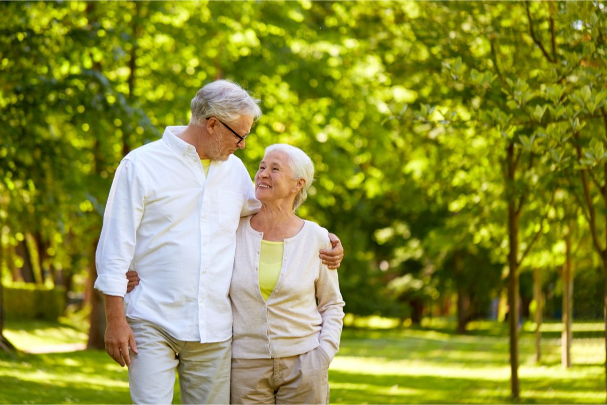 An older couple walking through a park.