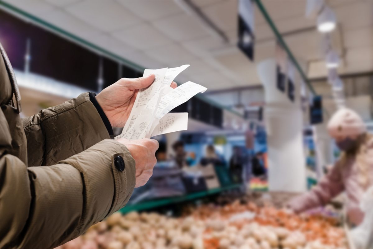 A person holding up a receipt in a supermarket.