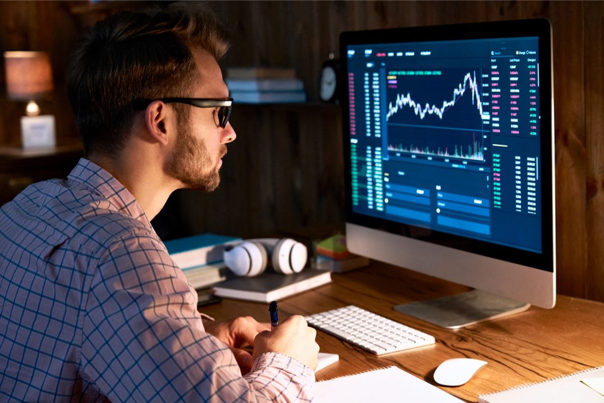 A man looking at graphs and data on a computer screen.