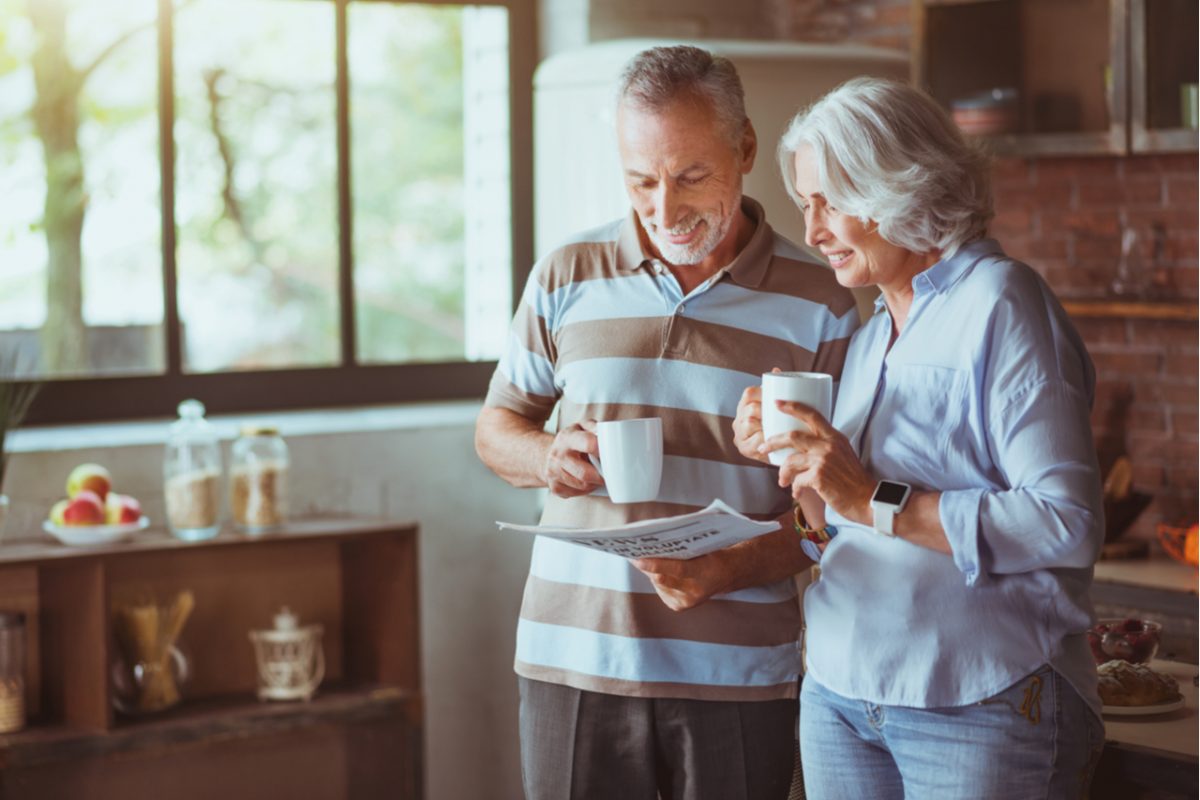 A couple drinking coffee and looking at some paperwork.