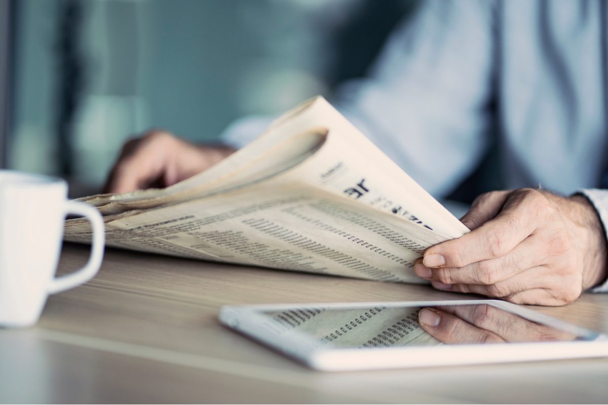 A man reading a newspaper at a table.