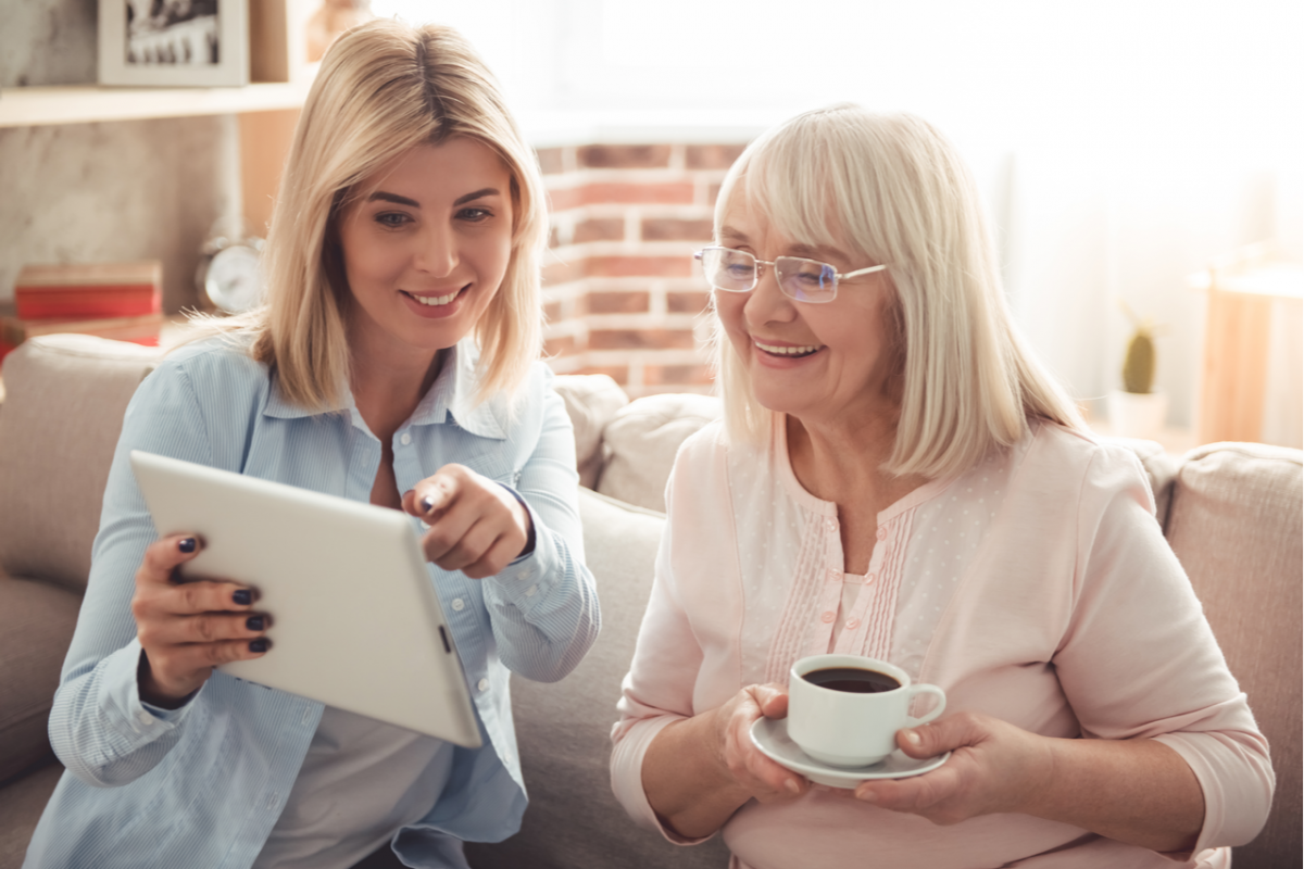 A young adult showing her mum something on a tablet.