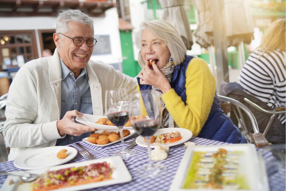 A couple laughing together as they eat al fresco.