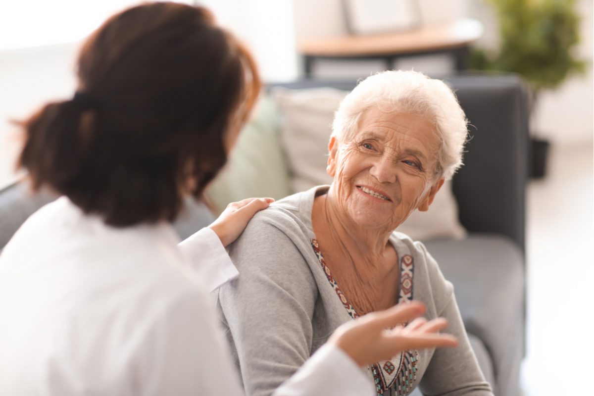 An older woman talking to a doctor at home.