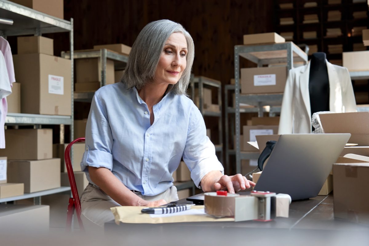 A woman working on a laptop in a warehouse.