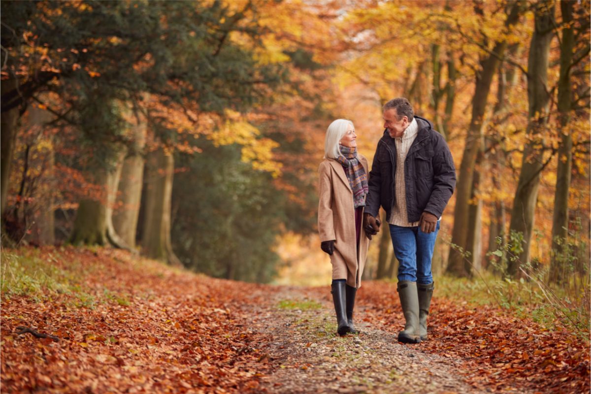 An older couple walking through woodland.
