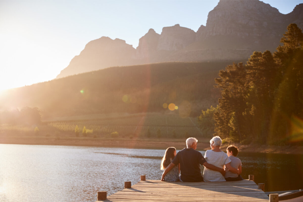 Children sitting with their grandparents on a jetty.