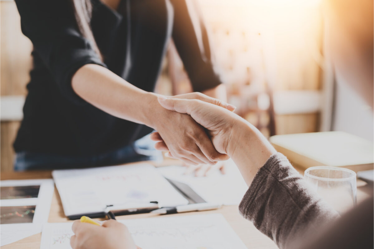 Two people shaking hands in an office.