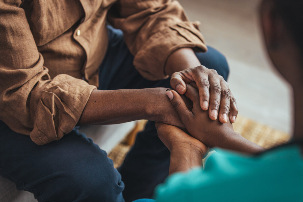 An elderly person and a young person holding hands.