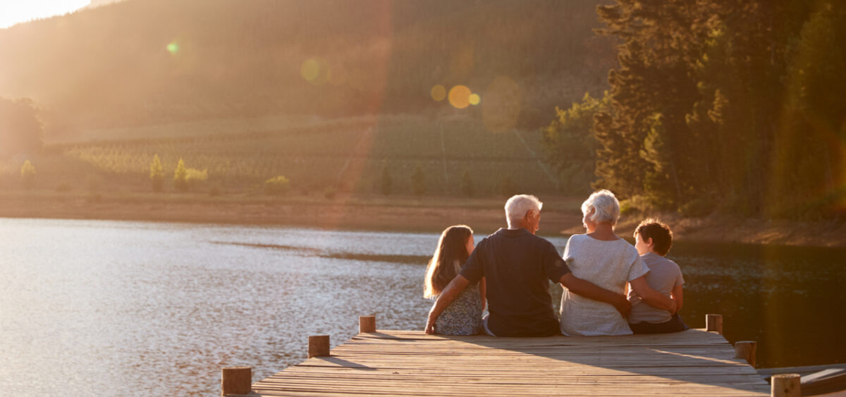 Grandparents sitting on a jetty with their grandchildren.