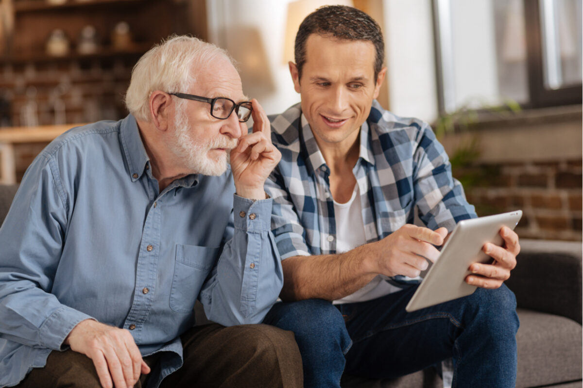 Young man showing his elderly father something on a tablet