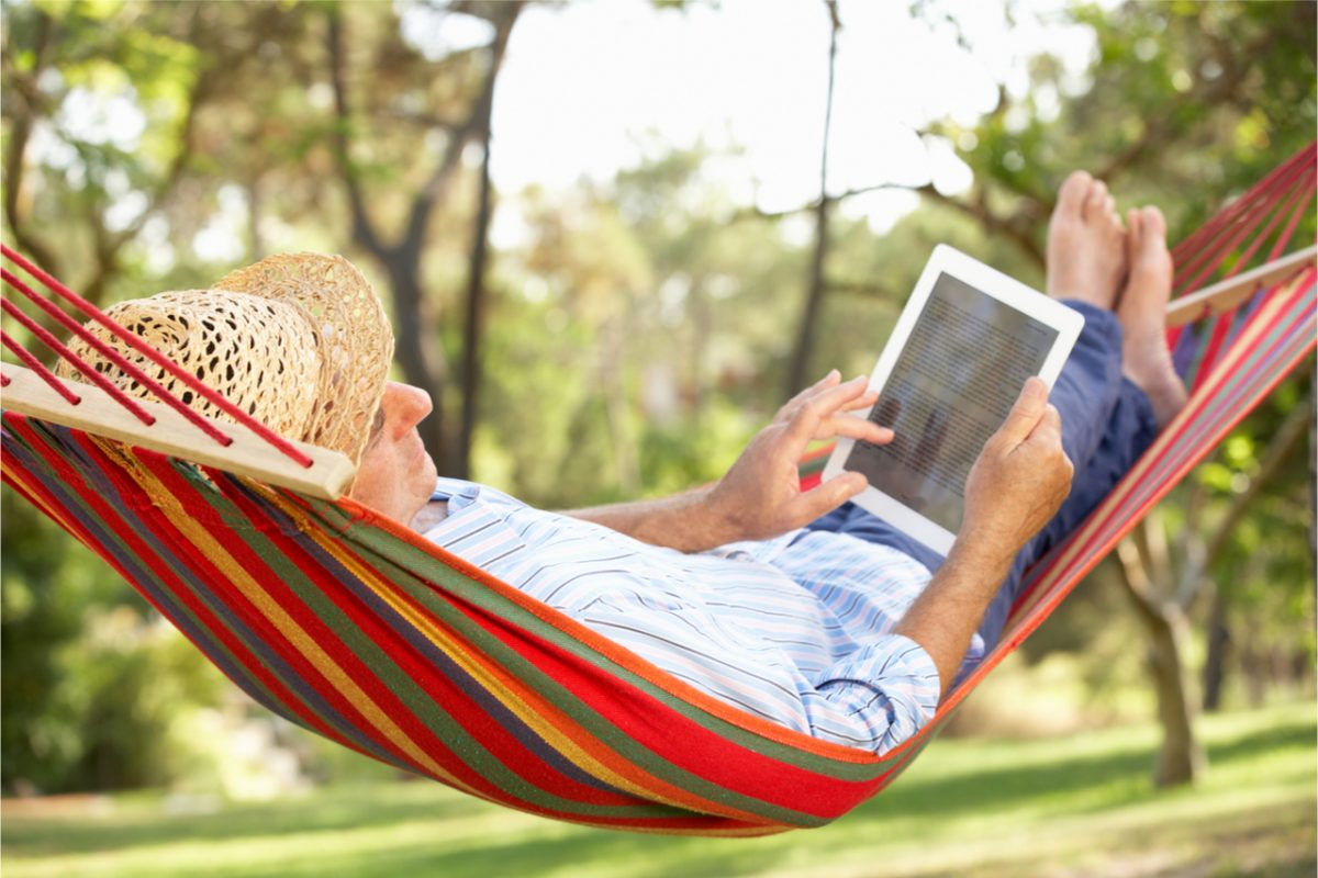 A man in a hammock using a tablet.