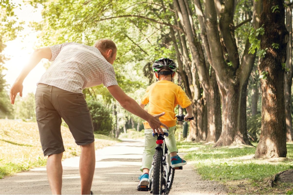 A father teaching a child to ride a bike.
